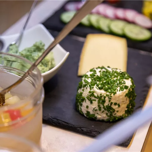 A beautiful snack table with fresh ingredients. There are herb cream, cheese, and colorful vegetable slices.