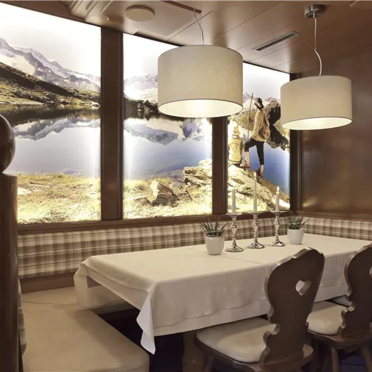 A cozy restaurant with a white table and comfortable chairs. The walls are decorated with landscape pictures and modern lighting.