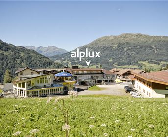 A picturesque view of a mountain hotel nestled in a green landscape. The majestic mountains frame the scene and convey a serene atmosphere.
