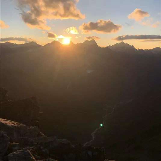 An impressive sunset over the mountains. The sun beams between the peaks, creating a picturesque atmosphere.