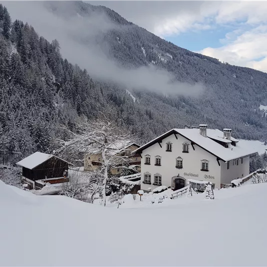 A snowy valley with a white house and fog in the mountains. The landscape is picturesque and wintry.