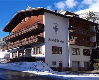 A cozy chalet in winter covered in snow. The sky is clear and blue.
