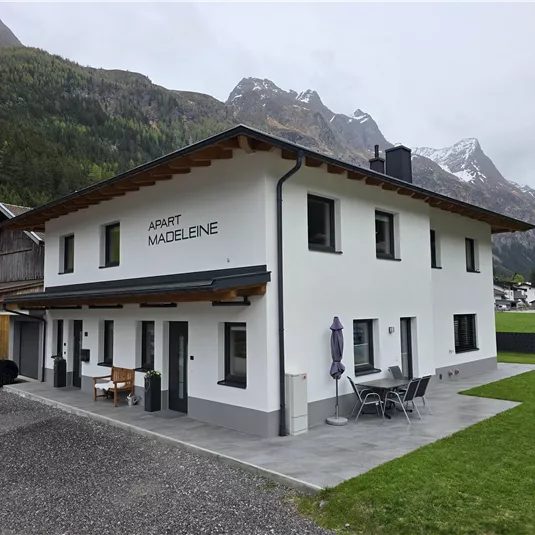 Ein modernes Haus in den Bergen mit einem großen Garten. Die Umgebung ist grün und bietet einen schönen Blick auf die Berge.