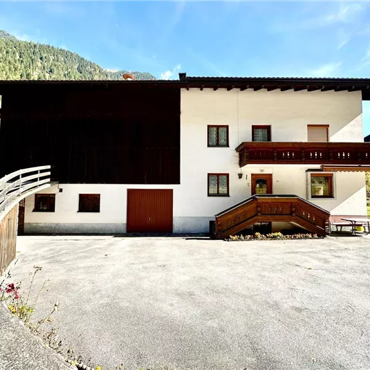 A cozy house in the mountains with a modern design. The surrounding landscape is green and tranquil.
