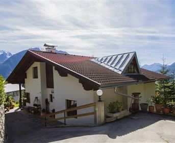 Ein schönes Haus mit einem modernen Dach, umgeben von Bergen und Bäumen. Die klare Landschaft bietet eine ruhige und friedliche Atmosphäre.