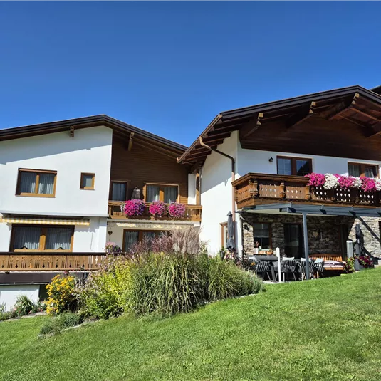 A beautiful house with a large garden and colorful flowers. The sky is clear and blue, which enhances the peaceful atmosphere.