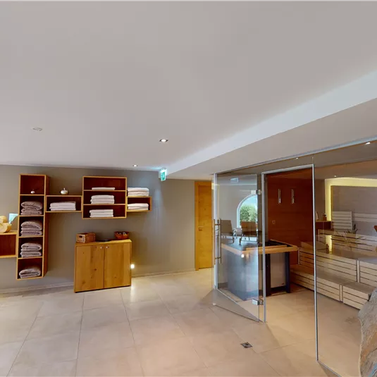 A modern spa area with a reception desk, shelves full of towels, and a relaxing ambiance. The soft lighting and clean lines create a calm atmosphere.