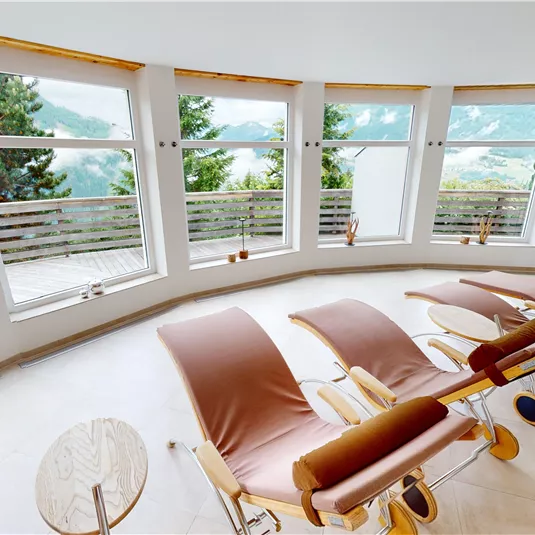 A bright relaxation room with large windows and a view of nature. Comfortable loungers invite you to relax.