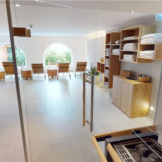 Ein moderner Entspannungsbereich mit Liegestühlen und großen Fenstern. Die Einrichtung ist hell und freundlich, ideal zum Relaxen.