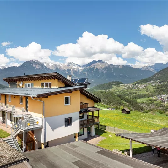 A beautiful view of a modern building in the mountains. Green meadows and a picturesque landscape surround the house.