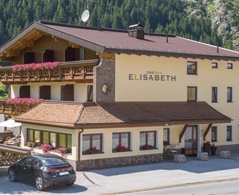 Ein charmantes Hotel mit dem Namen "Haus Elisabeth" in einer malerischen Berglandschaft. Der Außenbereich ist mit Blumen geschmückt und bietet eine einladende Atmosphäre.