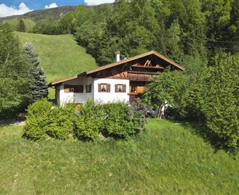 Ein charmantes Haus inmitten grüner Wiesen und dichter Bäume. Die Umgebung ist ruhig und idyllisch, ideal für die Naturverbundenheit.