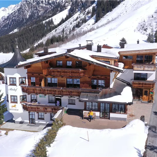 Ein gemütliches Chalet im Schnee, umgeben von majestätischen Bergen. Die Umgebung ist friedlich und winterlich mit einer schönen Berglandschaft.