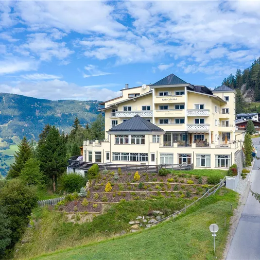 Ein schönes Hotel in den Bergen mit einer malerischen Aussicht. Umgeben von Bäumen und grünen Wiesen.