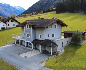 A modern house in a green, hilly landscape. In the background, mountains and a peaceful environment can be seen.