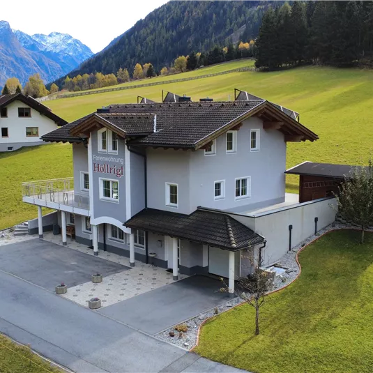 A modern house in a green, hilly landscape. In the background, mountains and a peaceful environment can be seen.