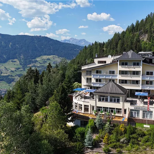 Ein modernes Hotel in den Bergen mit Blick auf das Tal. Umgeben von Wäldern und einer malerischen Landschaft.