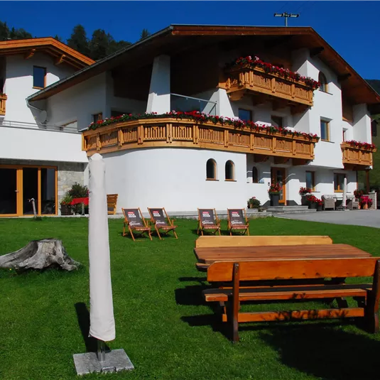 Ein gemütliches Haus im alpenländischen Stil mit Holzbalkonen. Der Garten ist schön angelegt und lädt zum Entspannen ein.