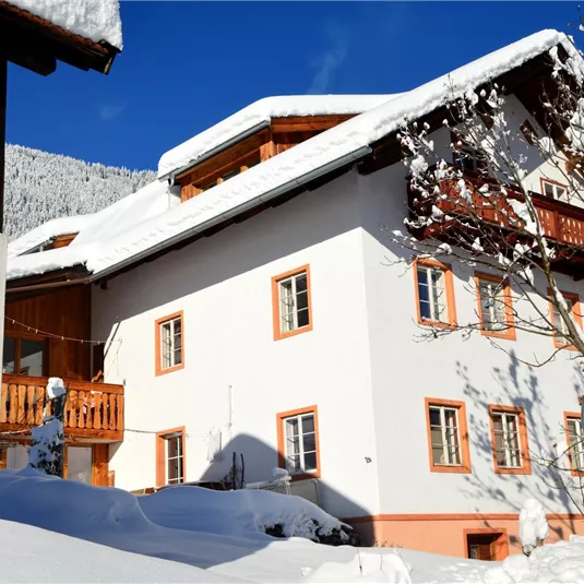 A charming house in the snow with a blue sky. The surroundings are quiet and wintry, perfect for a cozy atmosphere.