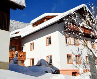 Ein charmantes Haus im Schnee mit einem blauen Himmel. Die Umgebung ist ruhig und winterlich, ideal für eine gemütliche Atmosphäre.