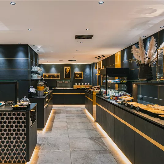 A modern and elegant restaurant with dark walls and high-quality lighting. Various dishes and drinks are attractively presented on the tables.