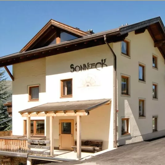 A charming building in the mountains with the inscription "Sonnick". The surroundings are filled with green hills and trees.