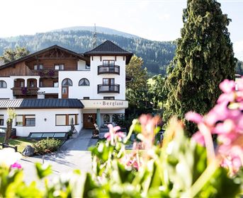 A charming house amidst mountains, surrounded by flowers. The Mediterranean architecture and the green surroundings give it an inviting character.