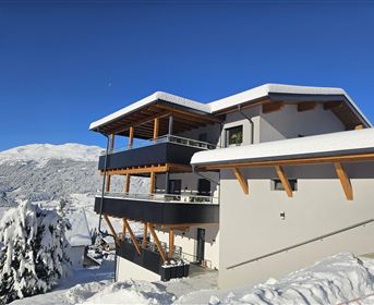 Ein modernes Gebäude in einer schneebedeckten Landschaft. Der klare blaue Himmel und die Berge im Hintergrund verleihen der Szene eine winterliche Atmosphäre.