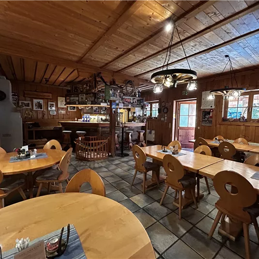 A cozy restaurant with wooden tables and chairs. The walls are decorated with photos, and the light is warm and inviting.