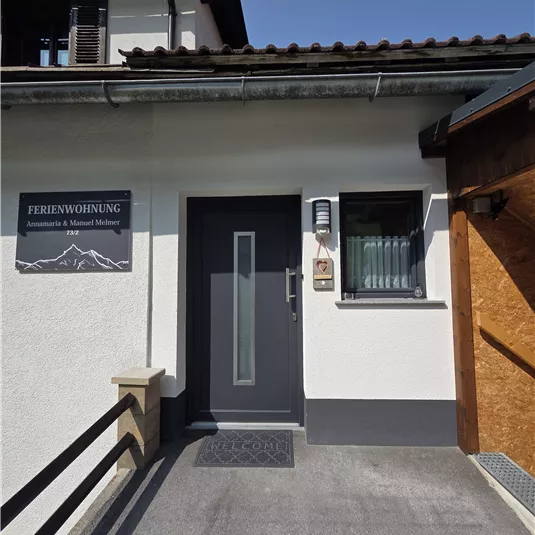 Eine Eingangstür zu einer Ferienwohnung in einem modernen Gebäude. Der Bereich ist gut beleuchtet und freundlich gestaltet.