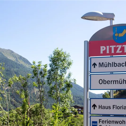 A signpost in the Pitztal with different directions. In the background, green mountains are visible.