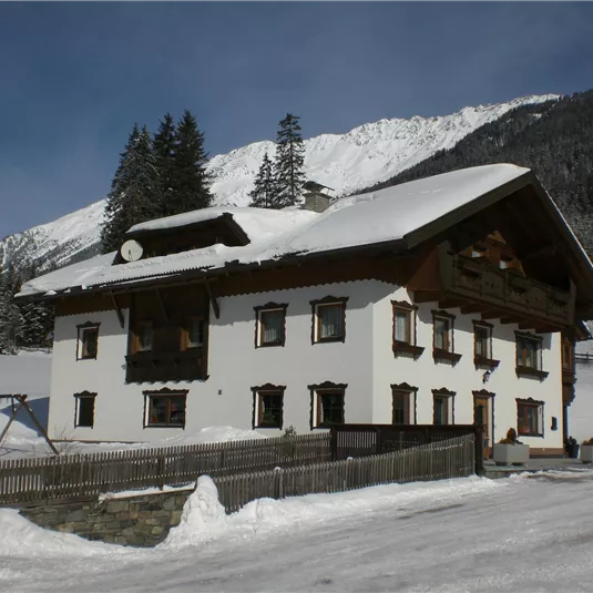 A beautiful building in alpine style, surrounded by snow-covered mountains. The sky is clear and the landscape looks peaceful.