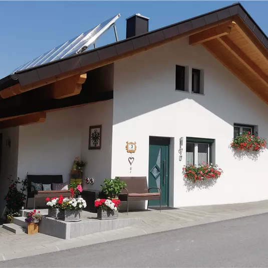 Ein gemütliches Einfamilienhaus mit einem schönen Garten. Bunte Blumen schmücken die Fenster und den Eingang.