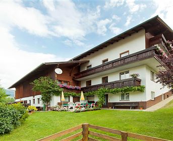 A charming building with balconies and colorful flowers. The garden is green and inviting, perfect for relaxing outdoors.