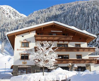 A cozy chalet in the snow with an impressive mountain panorama in the background. The facade is traditional and invites you to relax.