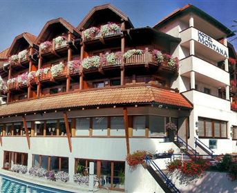 Ein charmantes Hotel mit mehreren Etagen, dekoriert mit Blumen. Vor dem Hotel befindet sich ein Pool und eine gepflegte Gartenanlage.