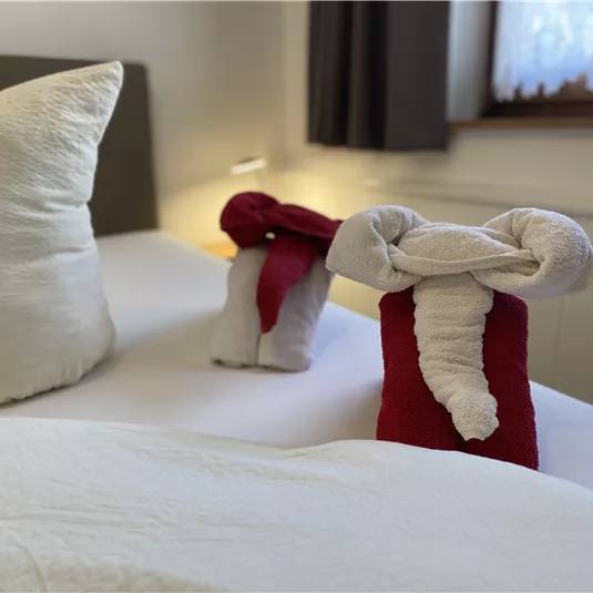 A cozy bed with decorative towel figures. The pillows are bright and harmoniously arranged.
