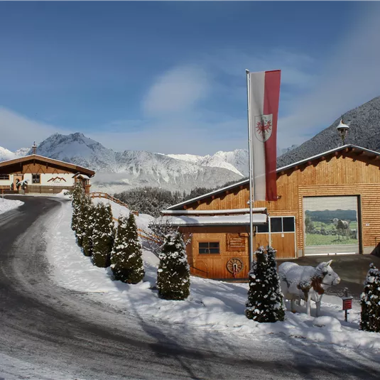 A beautiful wooden building in a winter landscape. Snow covers the surroundings and the mountains are visible in the background.