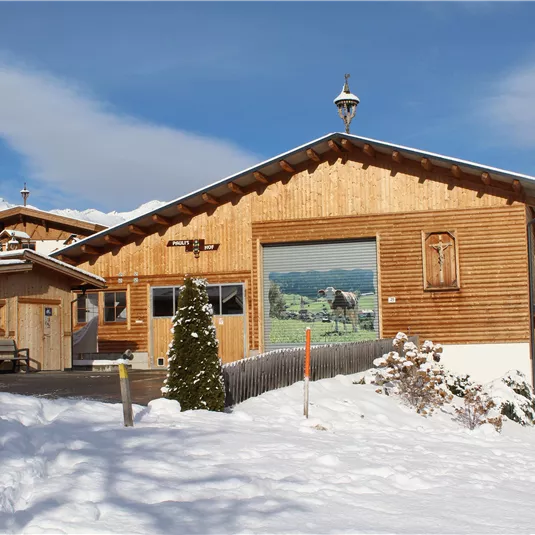 A beautiful wooden house in the snow with a clear blue sky. The surroundings are surrounded by mountains and a winter landscape.