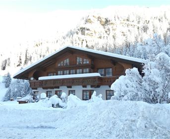 A beautiful wooden house in a snowy landscape. The snow is deep and the trees are frosty and white.