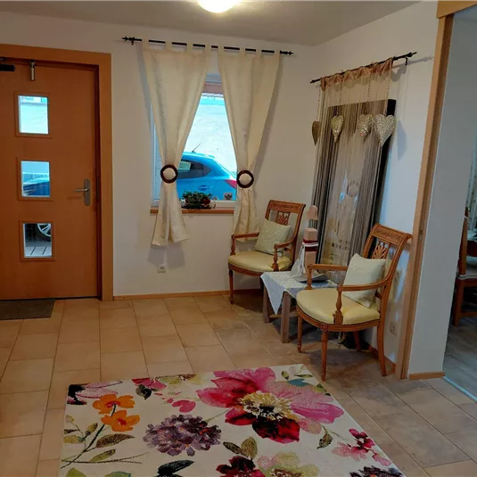 An inviting entrance area with a colorful rug and cozy chairs. Bright curtains allow light to flow in and create a friendly atmosphere.
