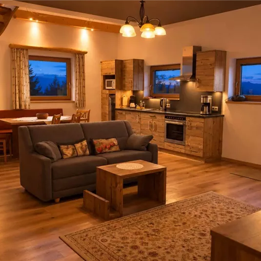 Eine gemütliche Wohnung mit Holzdetails und großen Fenstern. Der Wohnbereich verfügt über ein Sofa und einen Esstisch sowie eine Küchenzeile.