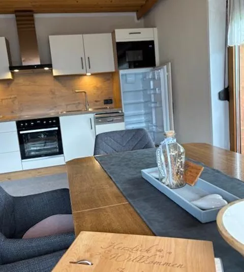 Eine moderne Küche mit Holzdecken und stilvollen Möbeln. Auf dem Tisch liegt ein Menübuch der Familie Schwart.