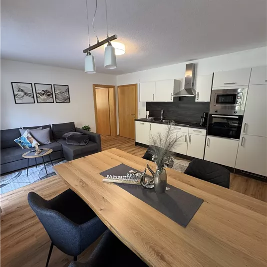 A modern apartment with an open living and dining area. The kitchen is bright and well-equipped, with a large dining table and cozy seating.