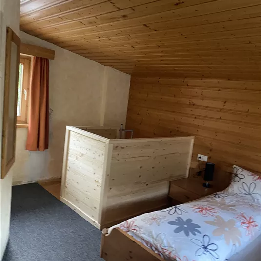 A cozy bedroom with a wooden ceiling and a double bed. The room has a balcony.