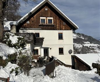 A charming house in the snow, surrounded by a winter landscape. The sky is clear and the atmosphere is calm.