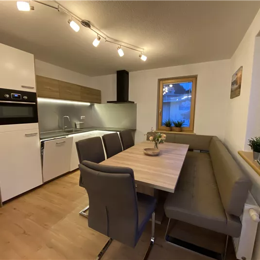 A modern kitchen with a bright dining area. The room is well lit and has large windows.