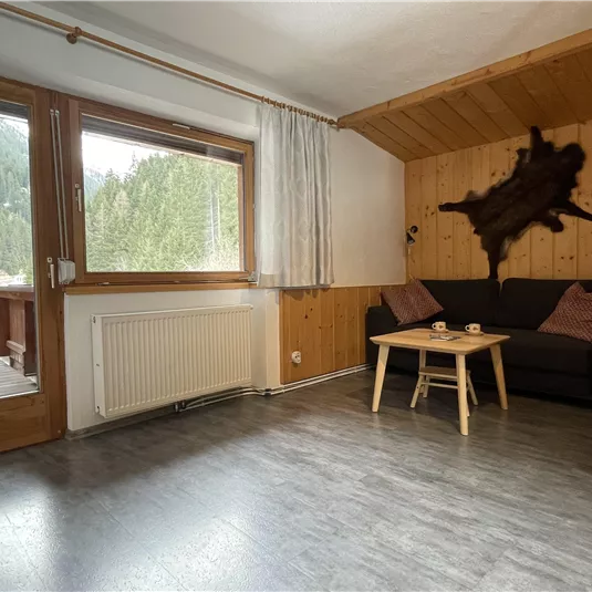 A cozy room with a sofa and a table. Through the windows, you can see a beautiful mountain landscape.