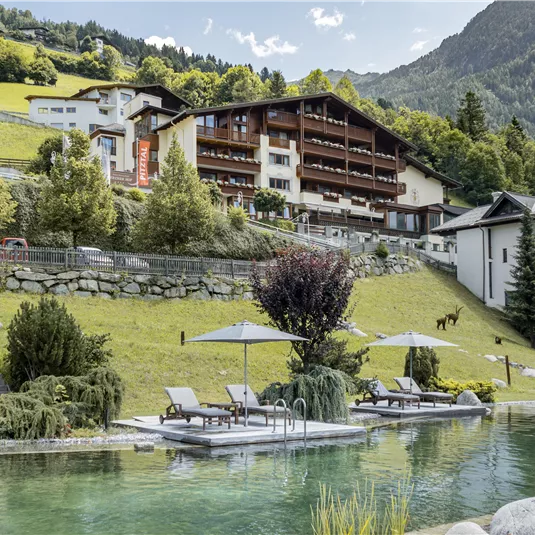 Ein malerischer Poolbereich mit Liegen, umgeben von gepflegten Gärten und Bergen im Hintergrund. Das Gelände strahlt Ruhe und Naturverbundenheit aus.