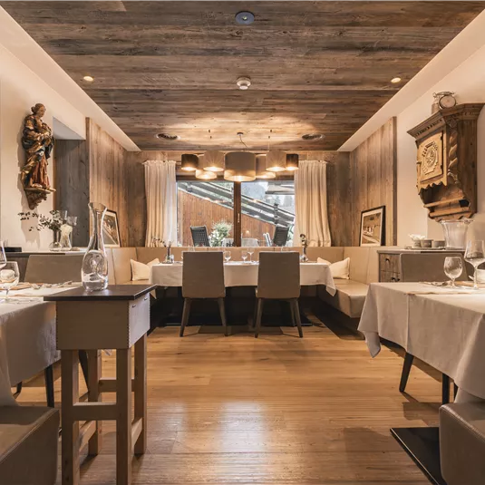 Ein elegantes Restaurant mit Holzdekor und stilvollem Ambiente. Die Tische sind schön gedeckt und es gibt einen Blick auf eine Außenterrasse.